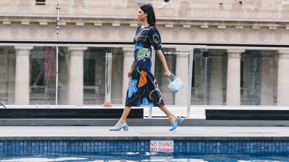 Person walking in a dress alongside a pool