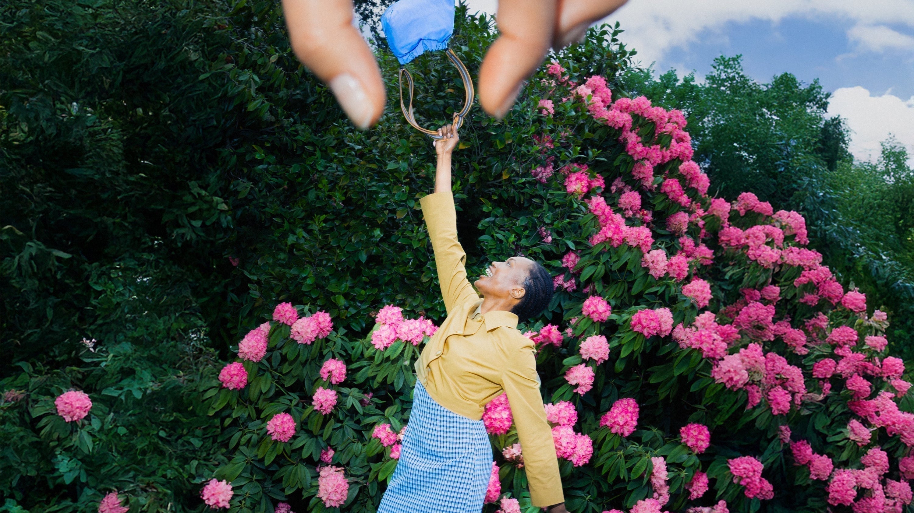 Person throwing a blue bag in the air with a large hand in the sky grabbing it.