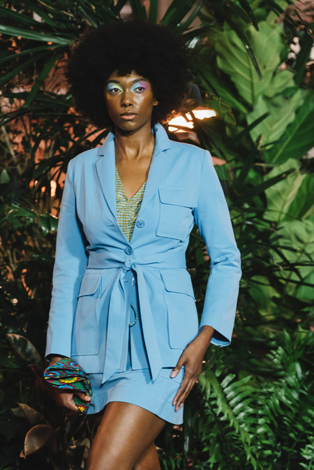 Person wearing a blue blazer and mini skirt walking down a runway