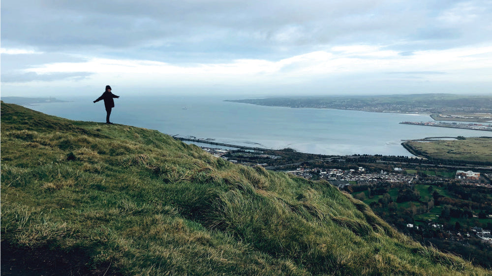 Person standing on top of a hill pictured from far away in Belfast