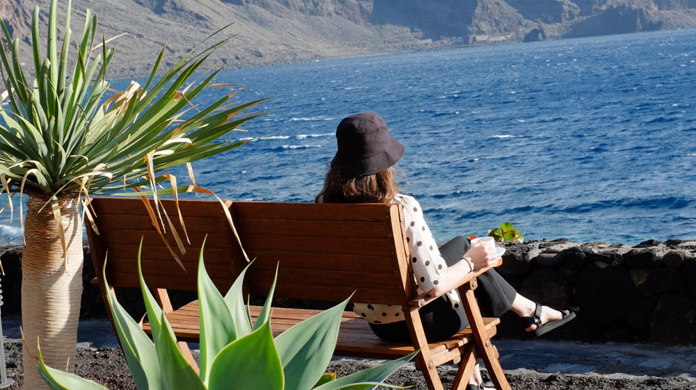 Person sitting on a bench looking at the ocean in El Hierro