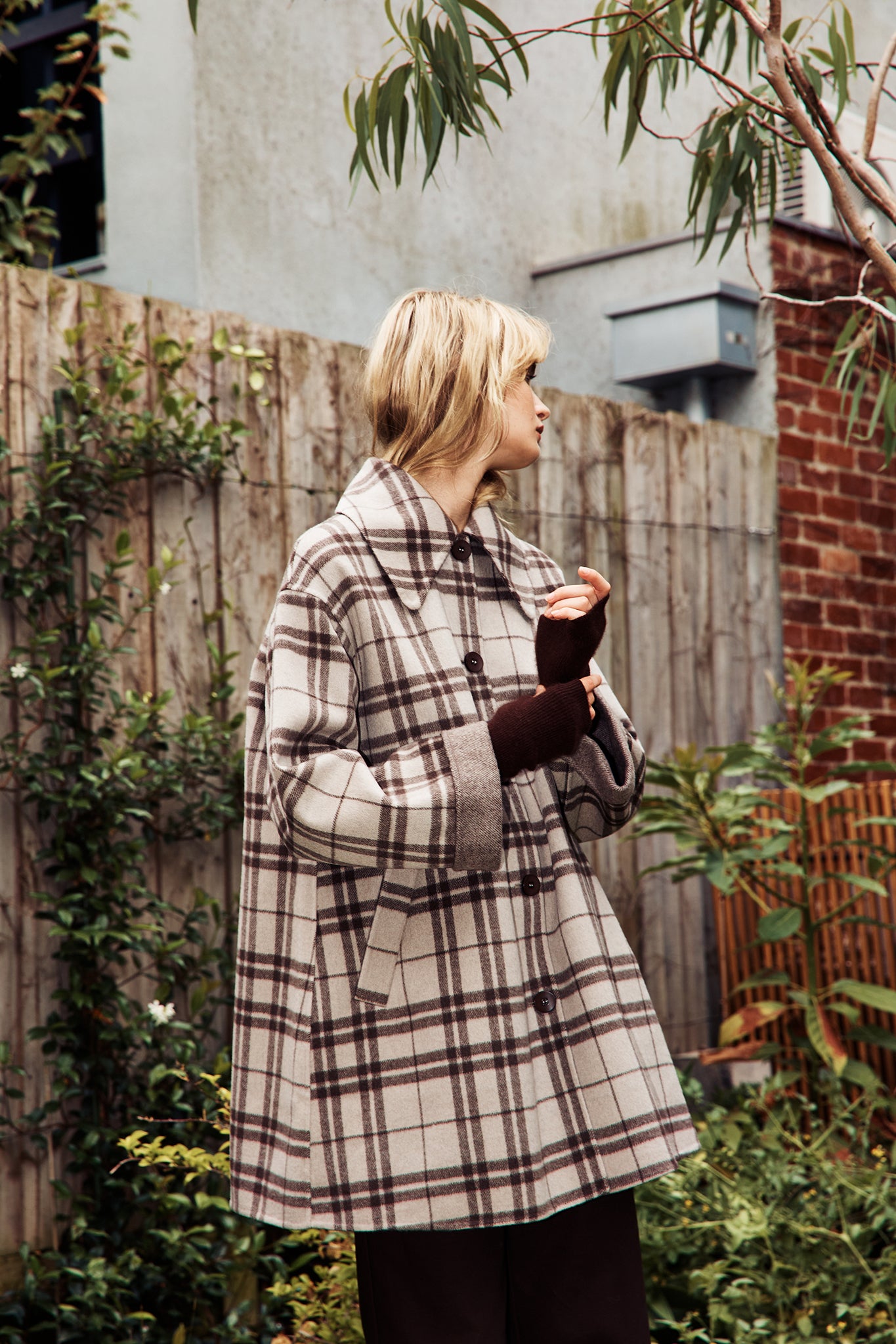Model wearing a beige and dark brown woollen coat in check
