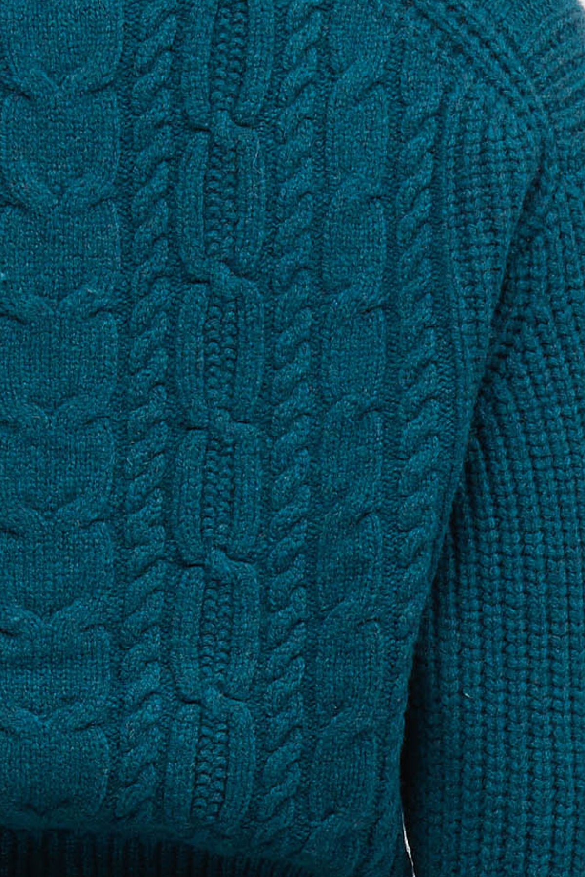 Woman wearing a cable knit cardigan in petrol colour