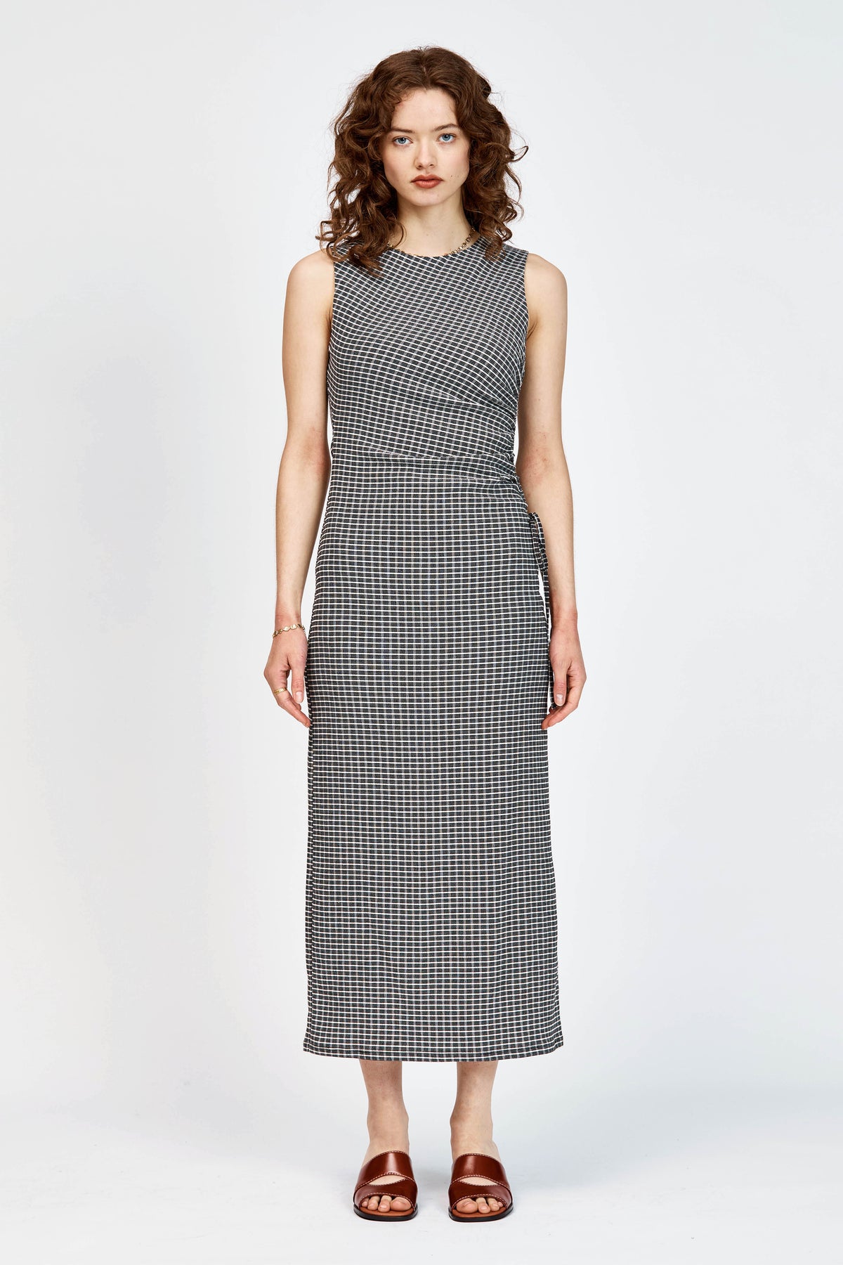 Model wearing fitted black and white check dress with waist tie detailing