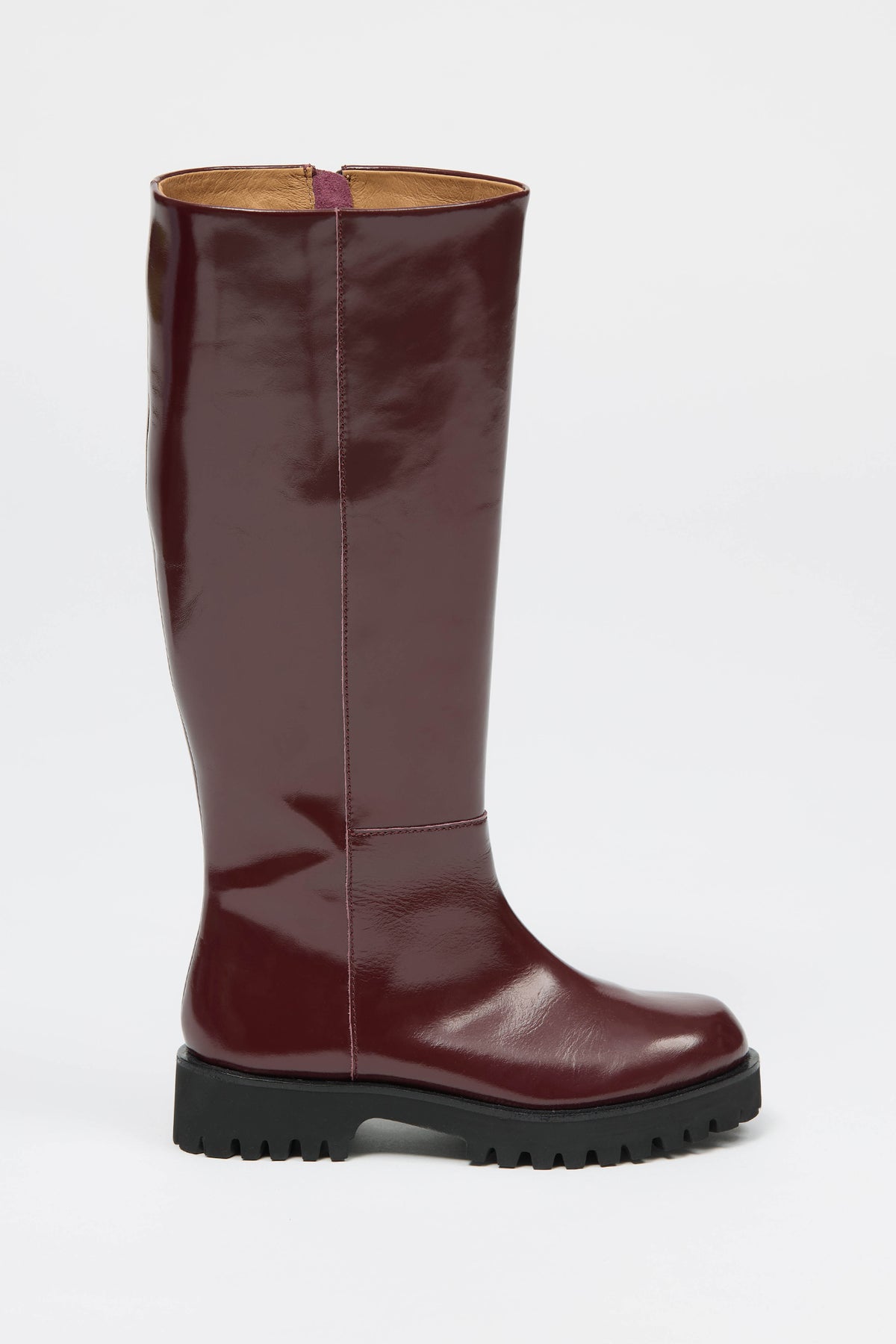 Knee high burgundy boot in a glossy material with a thick black sole