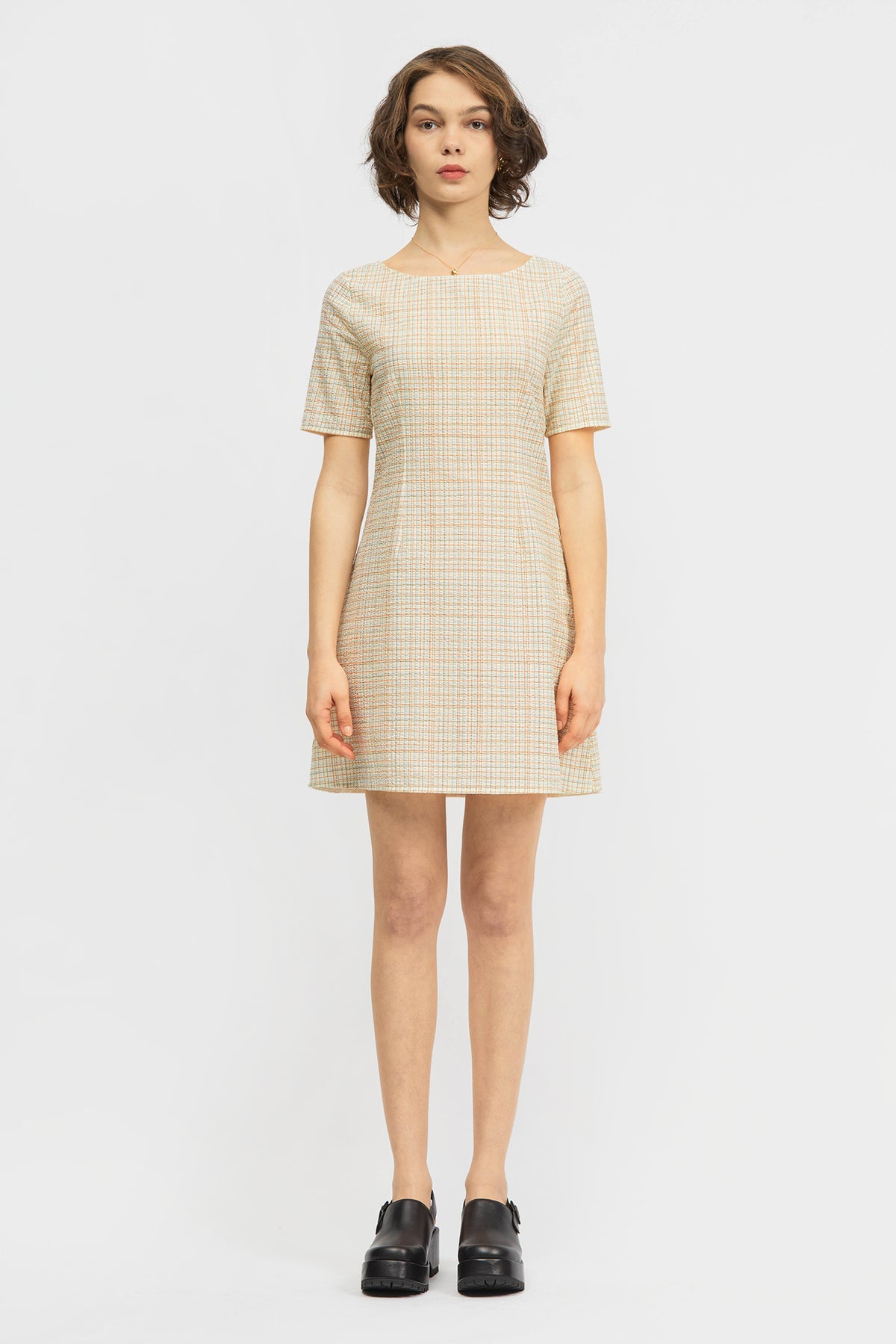 Woman wearing short dress in cream and red check