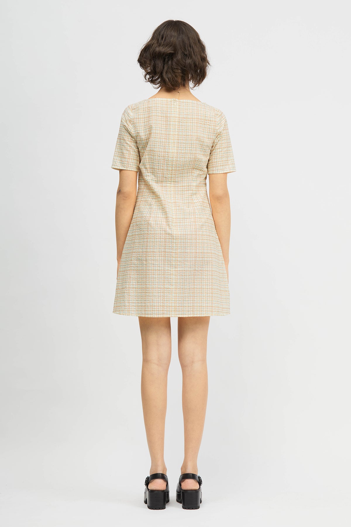 Woman wearing short dress in cream and red check