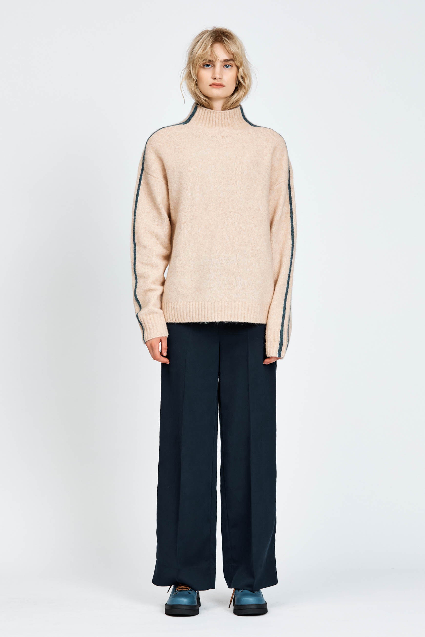 Woman wearing a soft knitted jumper in sand with blue stripe