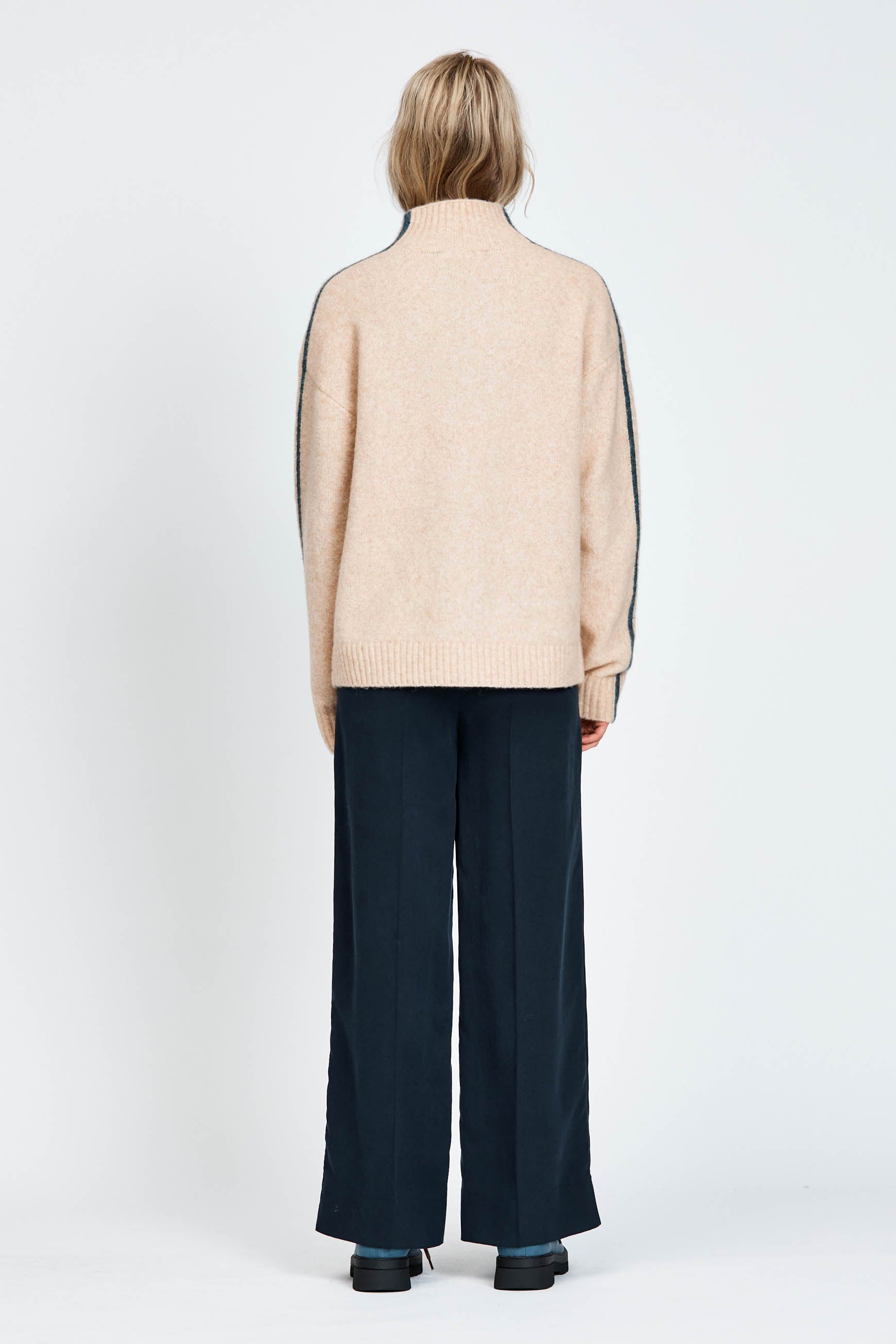 Woman wearing a soft knitted jumper in sand with blue stripe