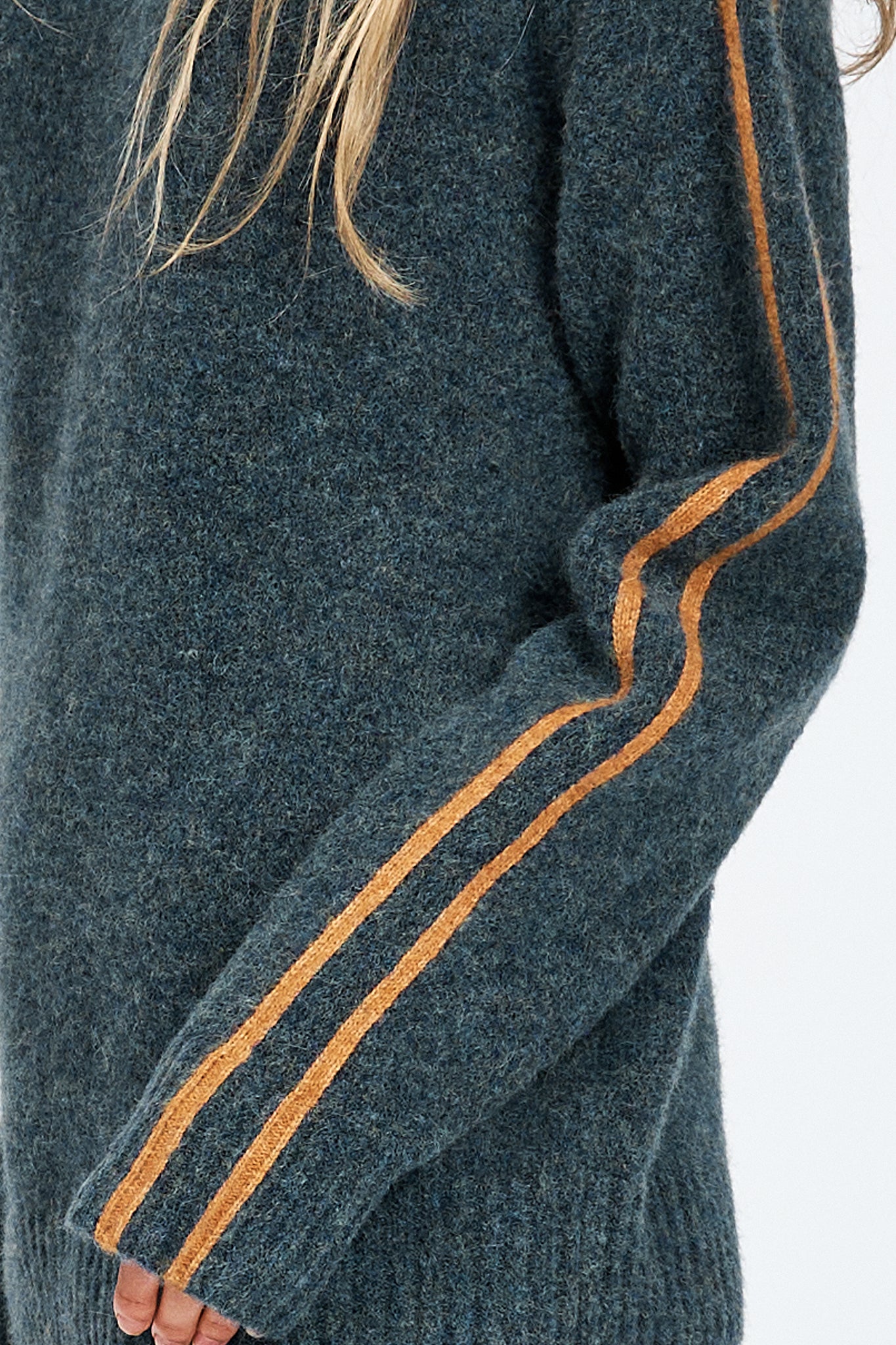 Woman wearing soft knitted jumper in blue with orange stripe