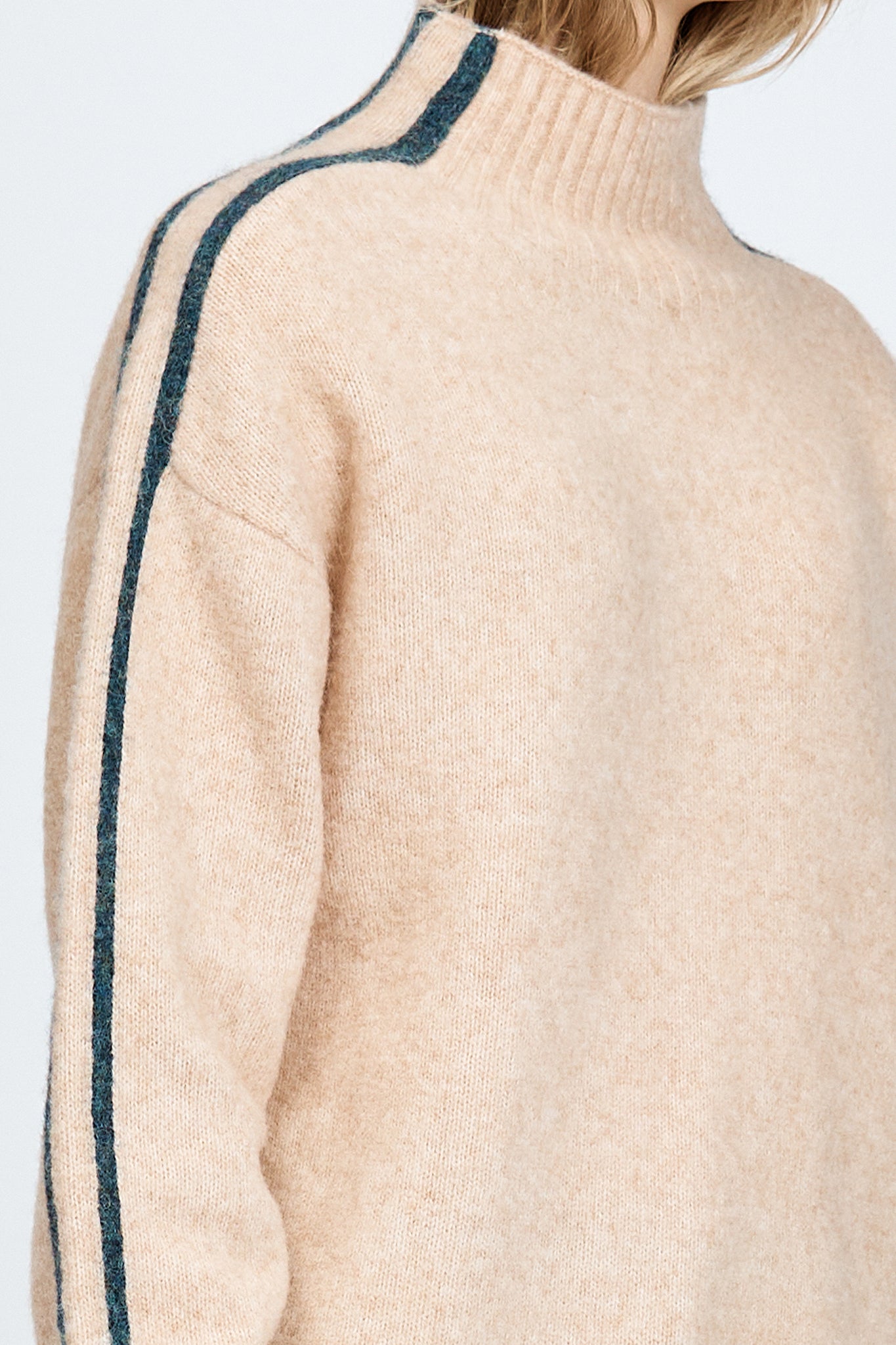 Woman wearing a soft knitted jumper in sand with blue stripe