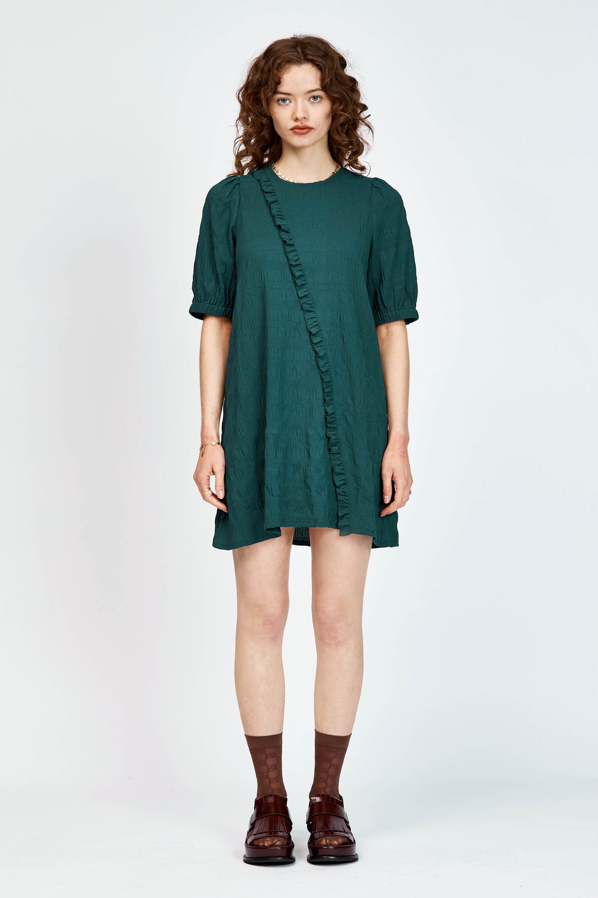 Model wearing a green mini dress with ruffle detailing