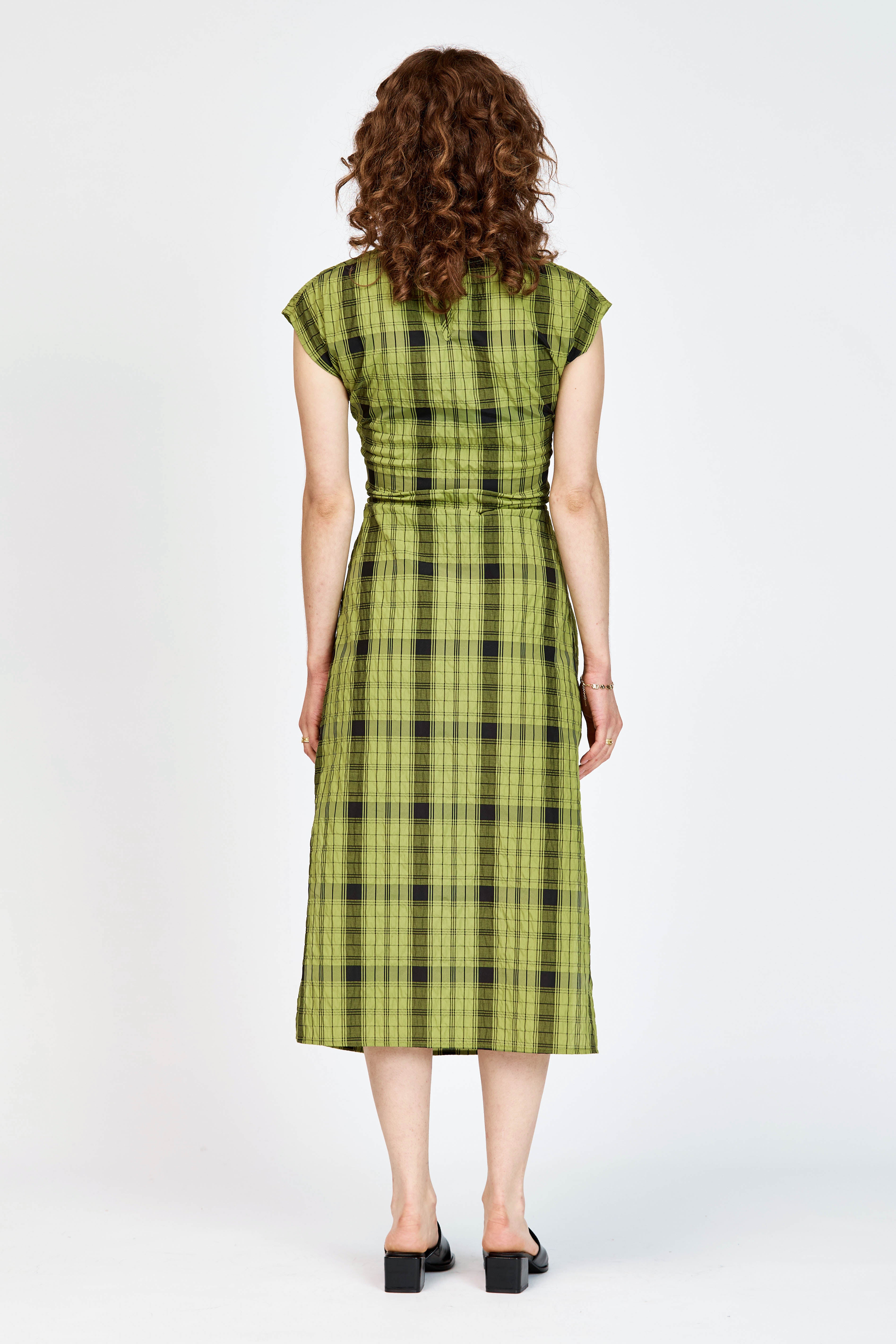 Model wearing an olive andblack check midi length dress with a tie waist detail
