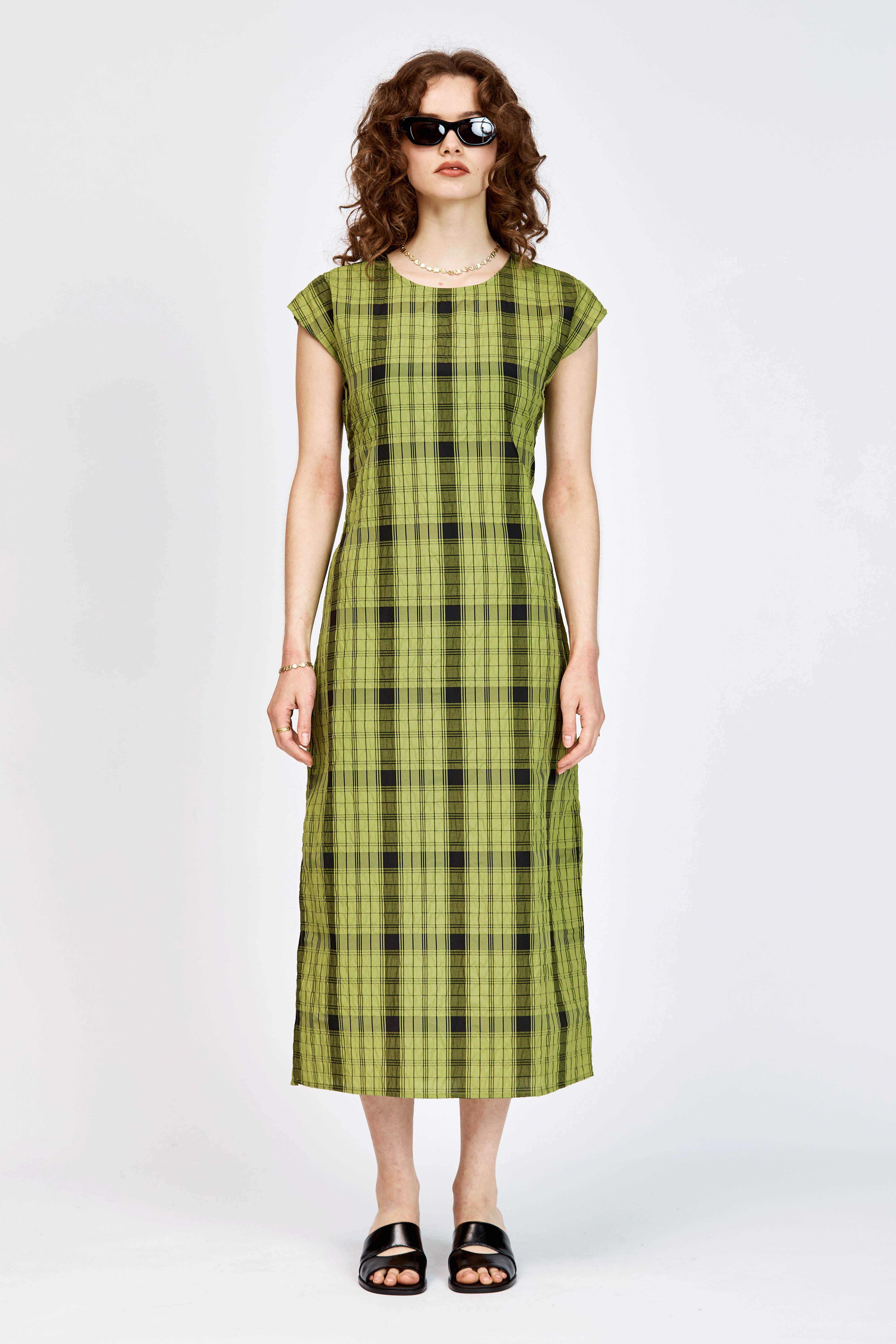 Model wearing an olive and black check midi length dress with a tie waist detail