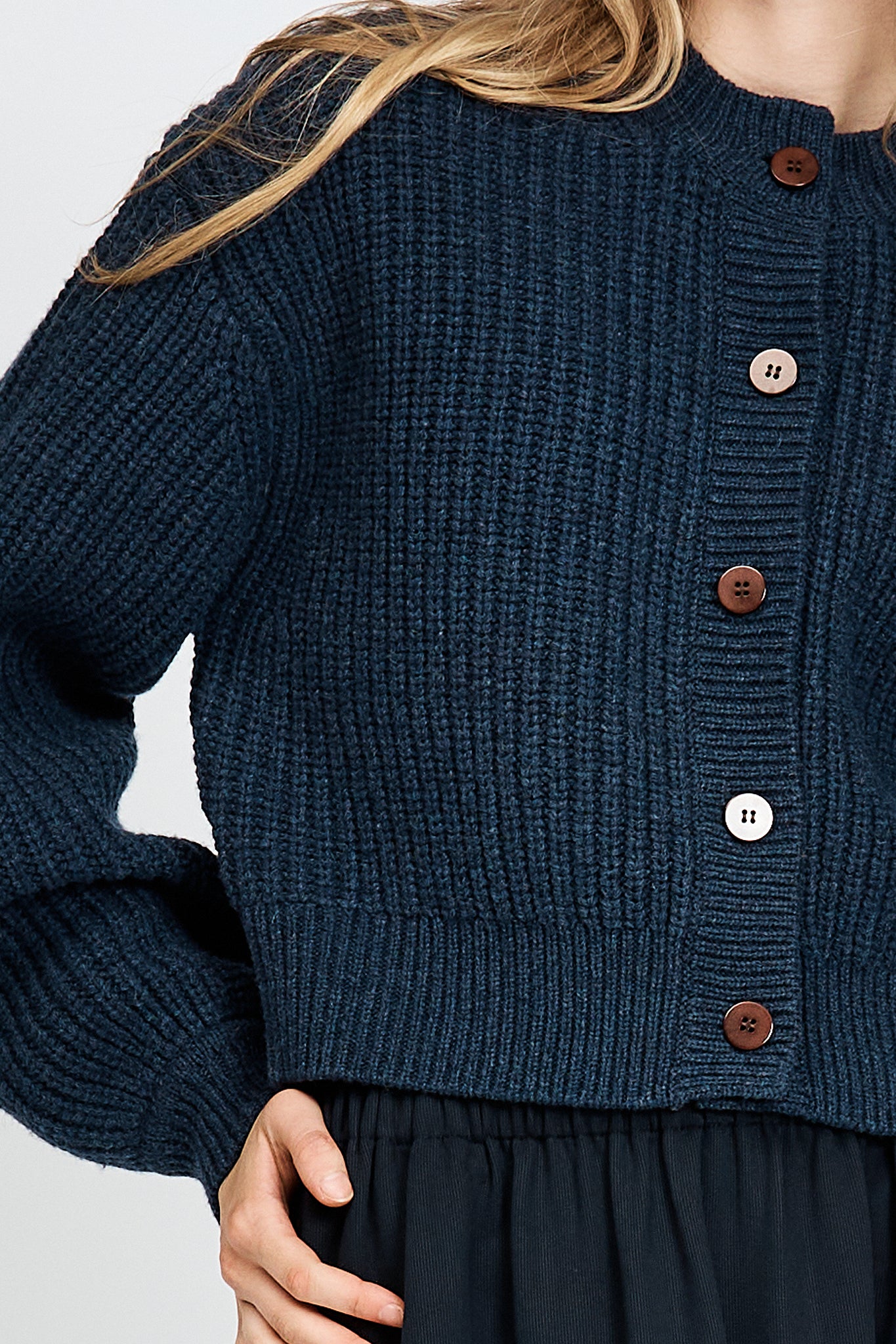 Woman wearing cable knit cardigan in navy