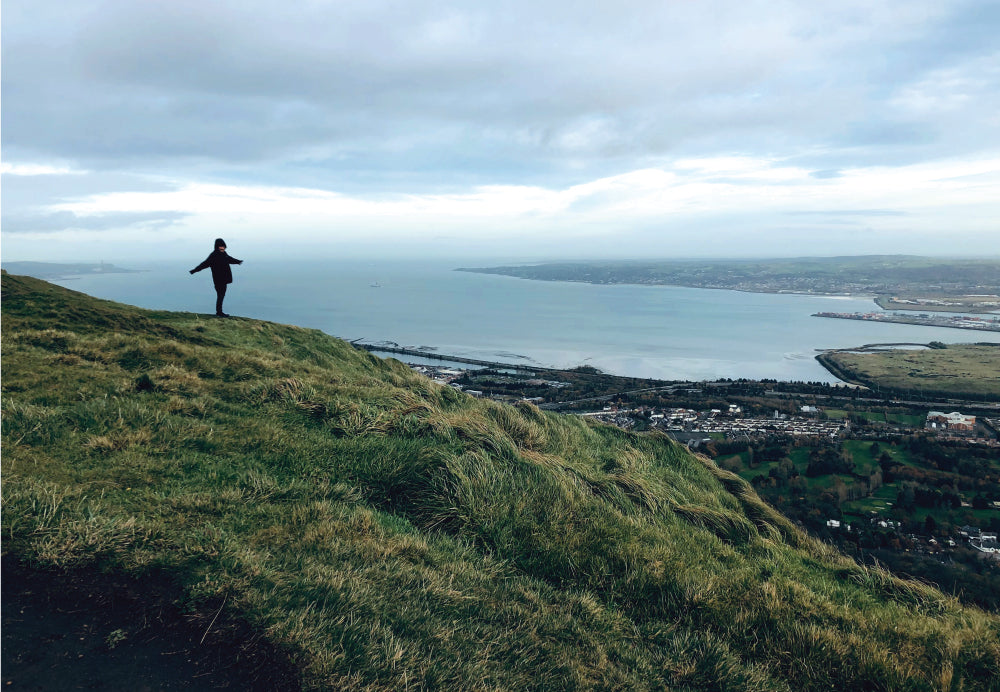 Person standing on top of a hill pictured from far away in Belfast