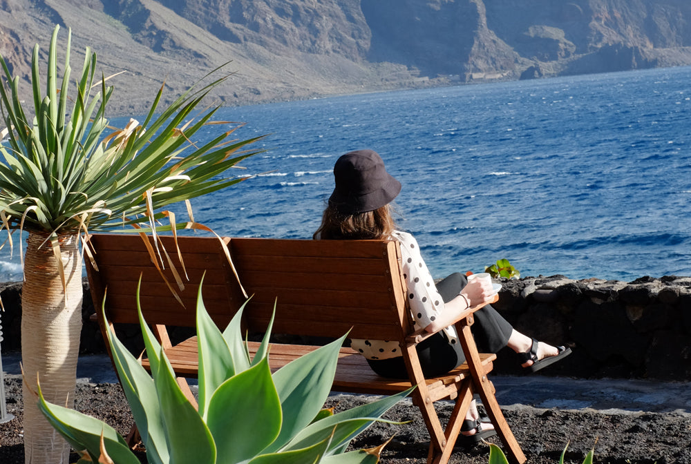 Person sitting on a bench looking at the ocean in El Hierro