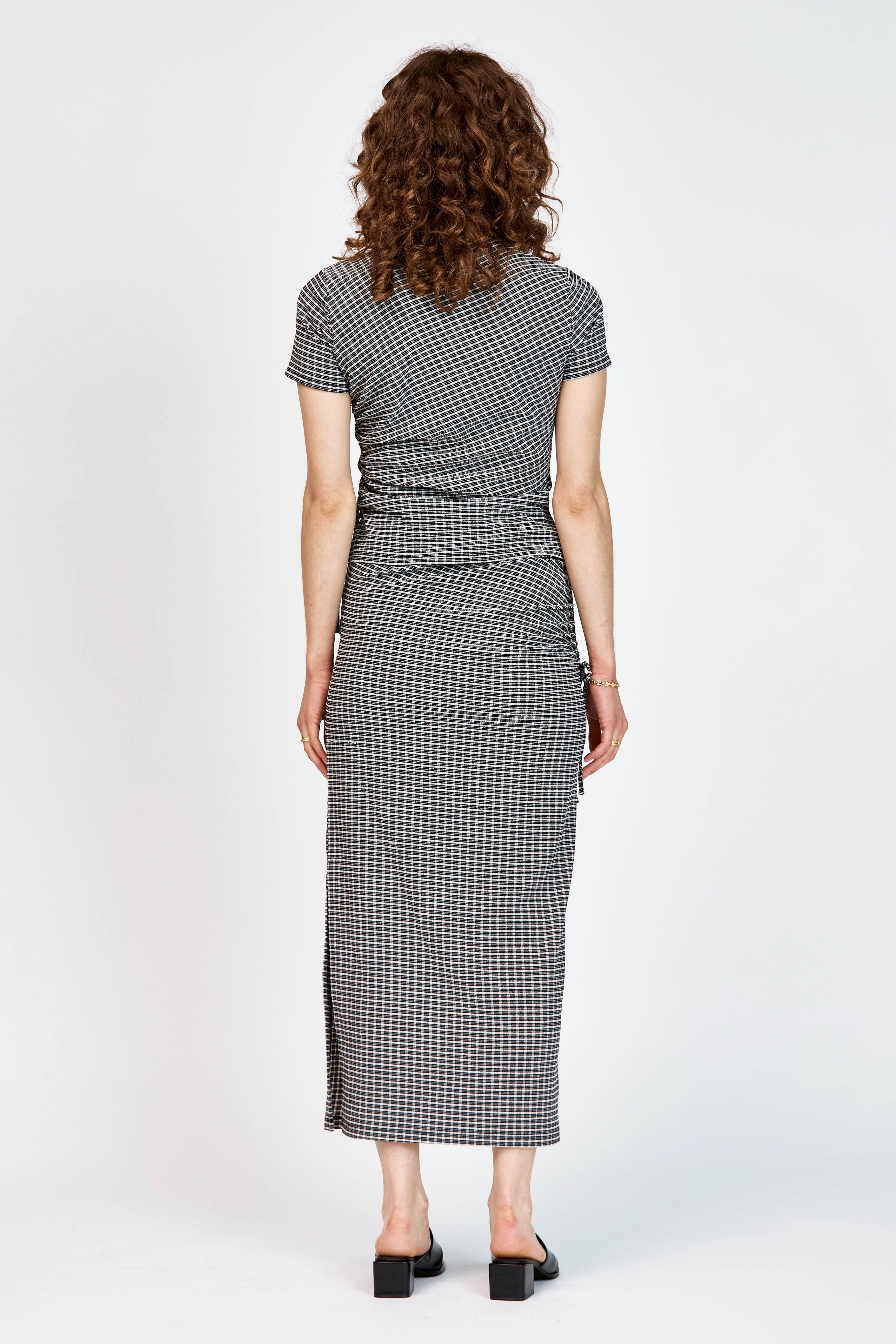Model wearing a matching top and skirt in black and white check fabric