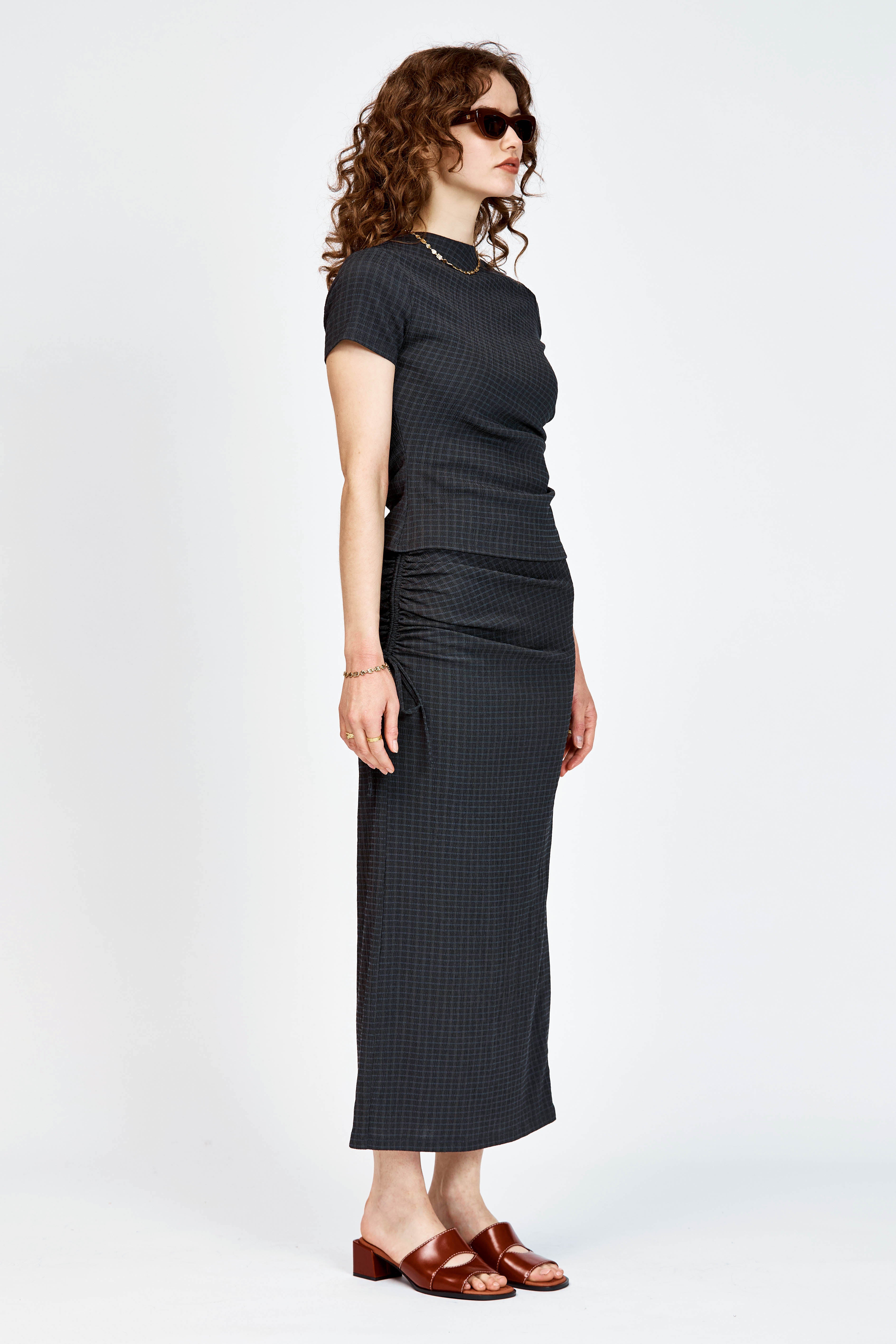 Model wearing a black skirt and top in matching black check fabric.