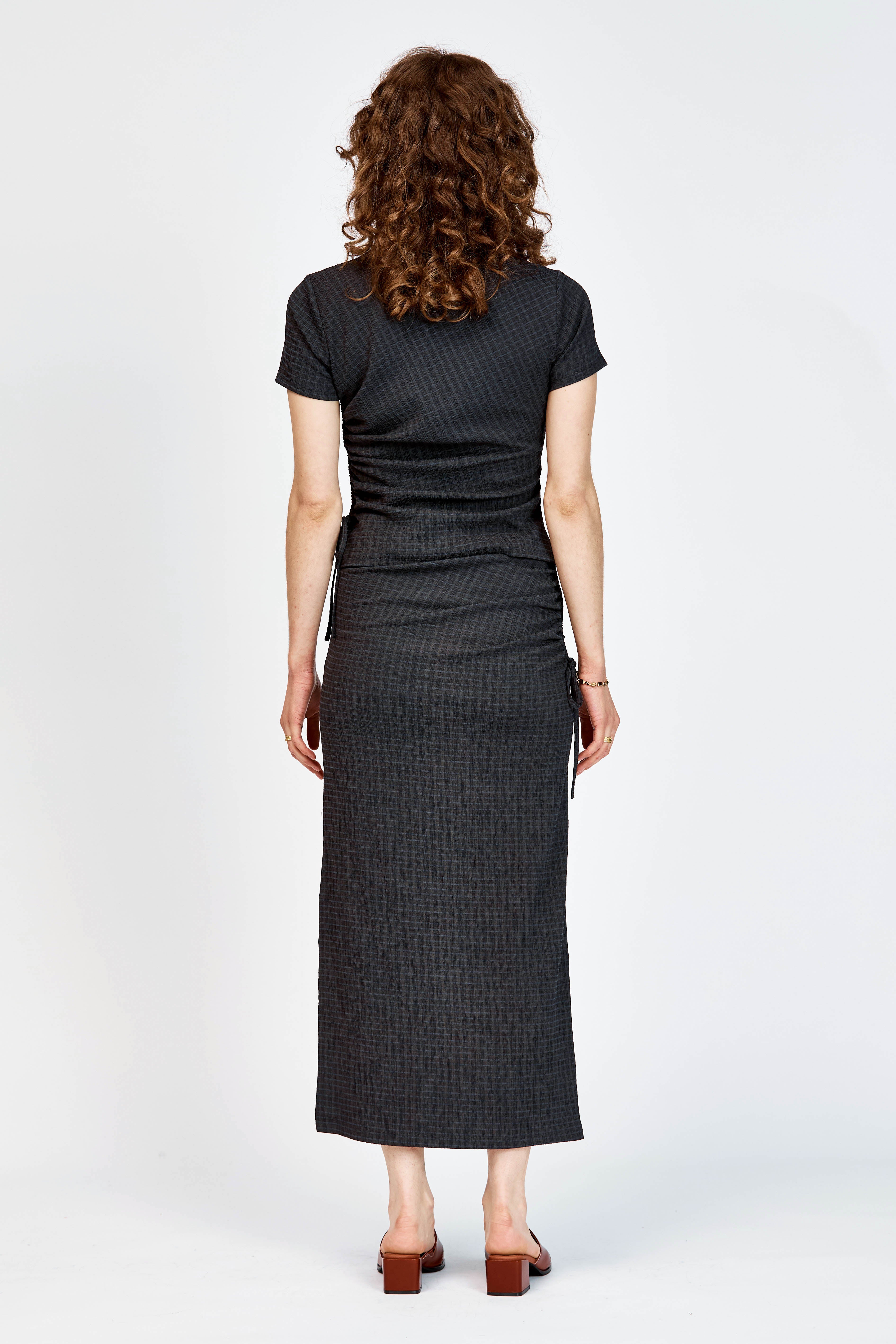 Model wearing a black skirt and top in matching black check fabric.
