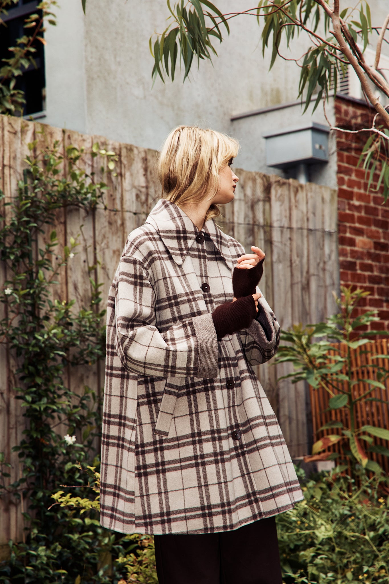 Model wearing a beige and dark brown woollen coat in check