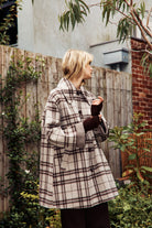 Model wearing a beige and dark brown woollen coat in check