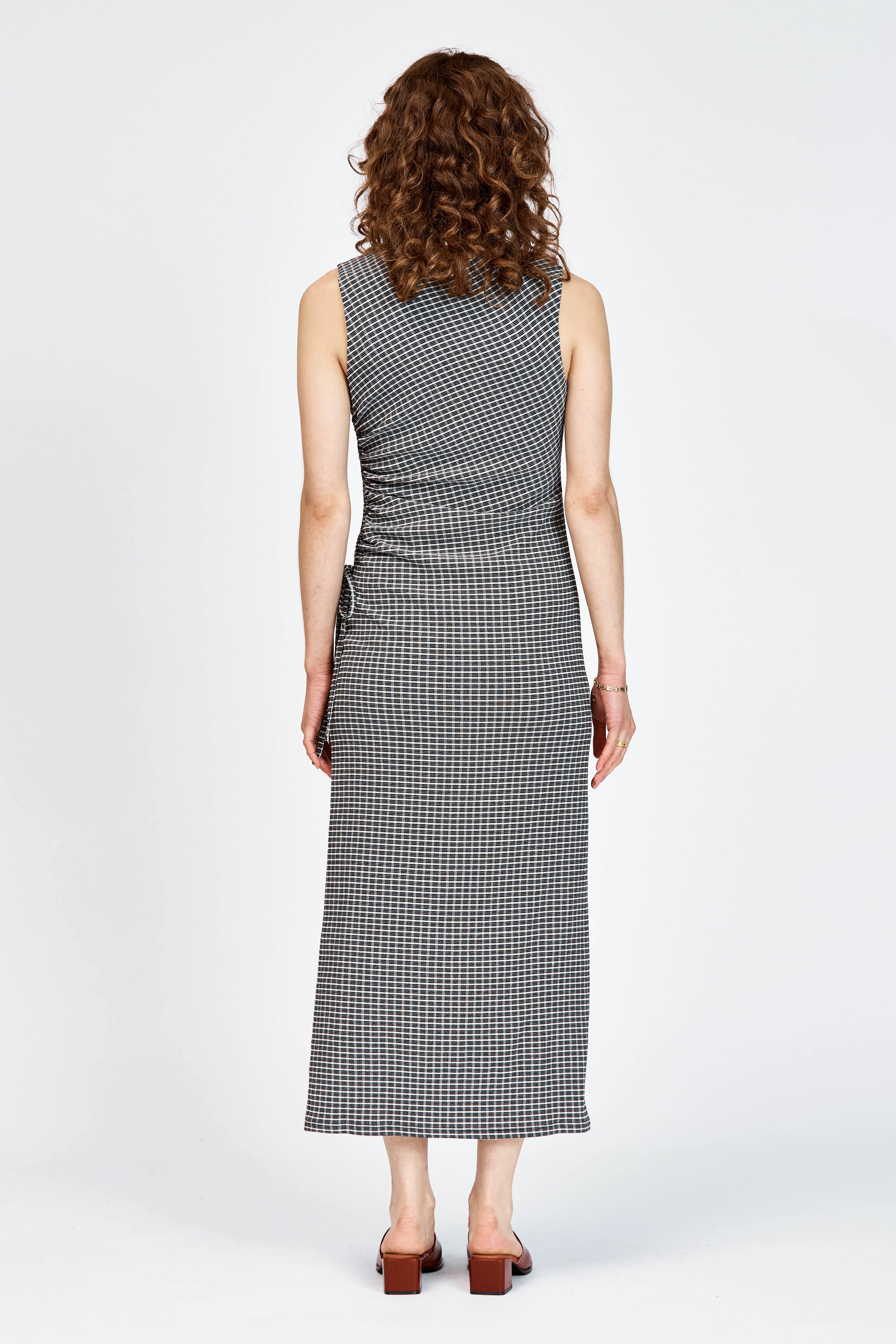 Model wearing fitted black and white check dress with waist tie detailing