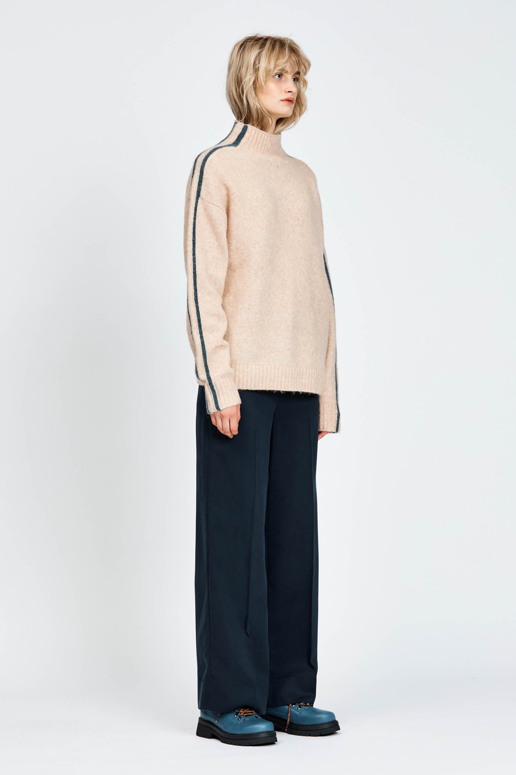 Woman wearing a soft knitted jumper in sand with blue stripe