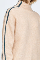 Woman wearing a soft knitted jumper in sand with blue stripe