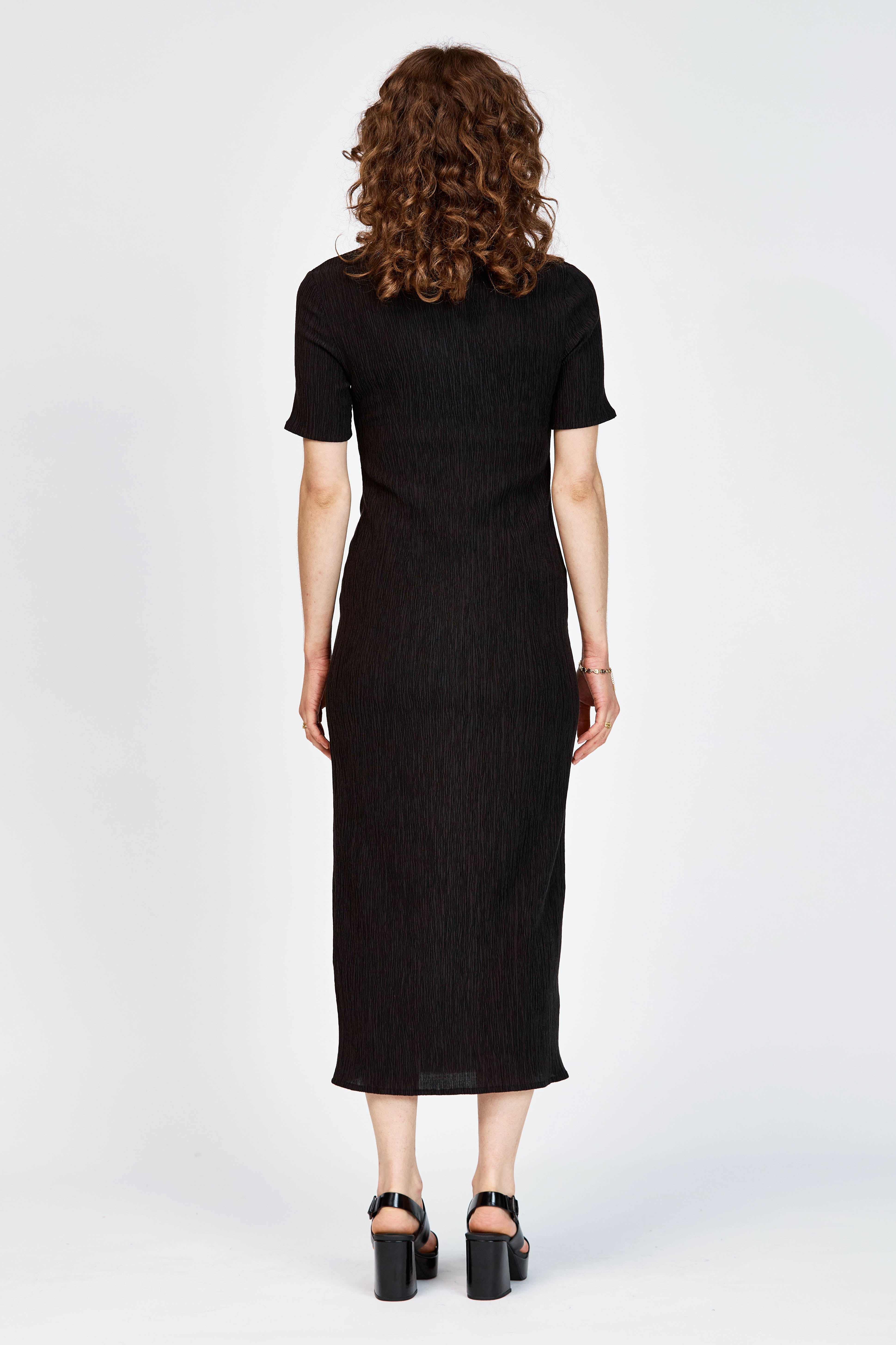 Model wearing a black short sleeve midi length dress with side slit