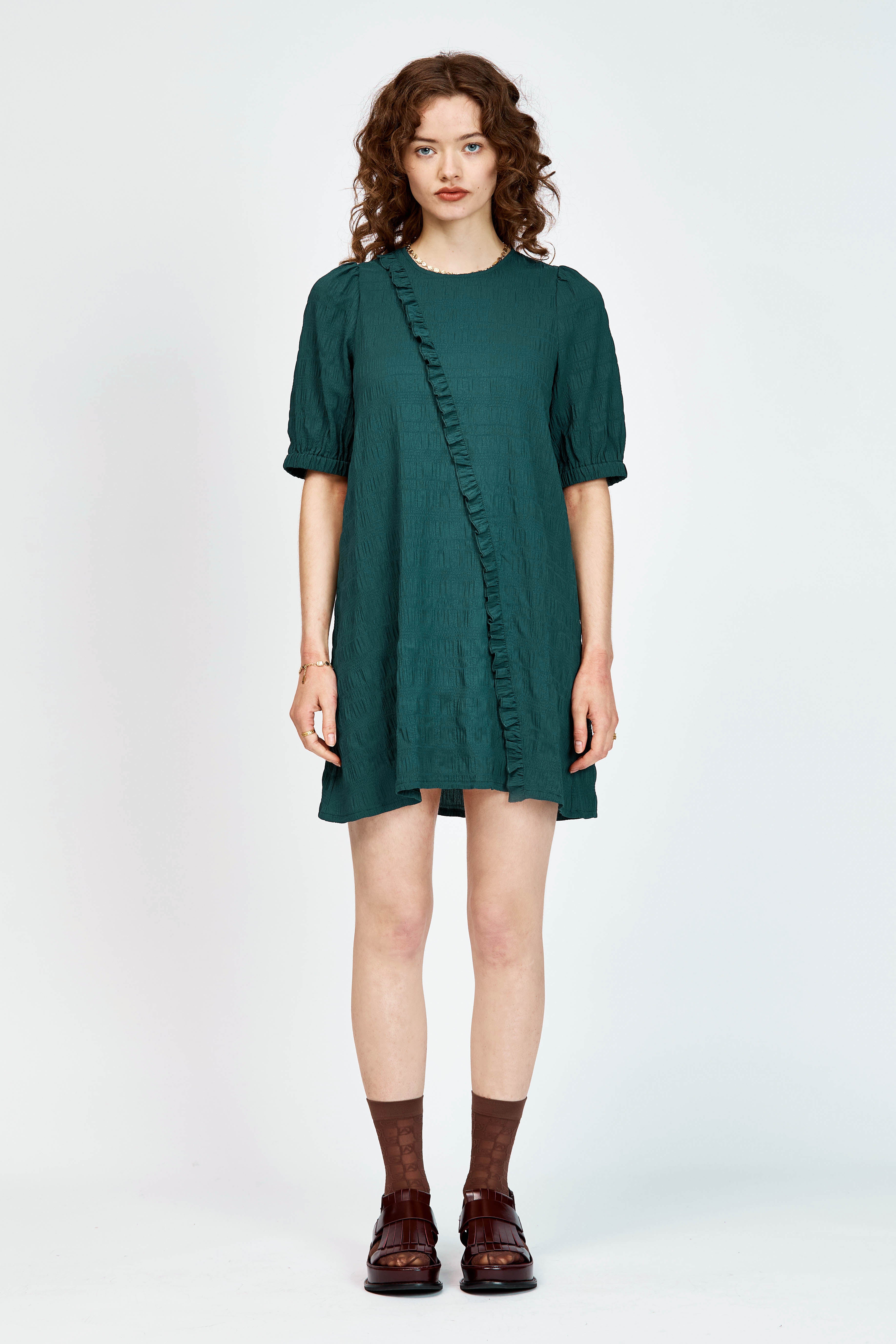 Model wearing a green mini dress with ruffle detailing