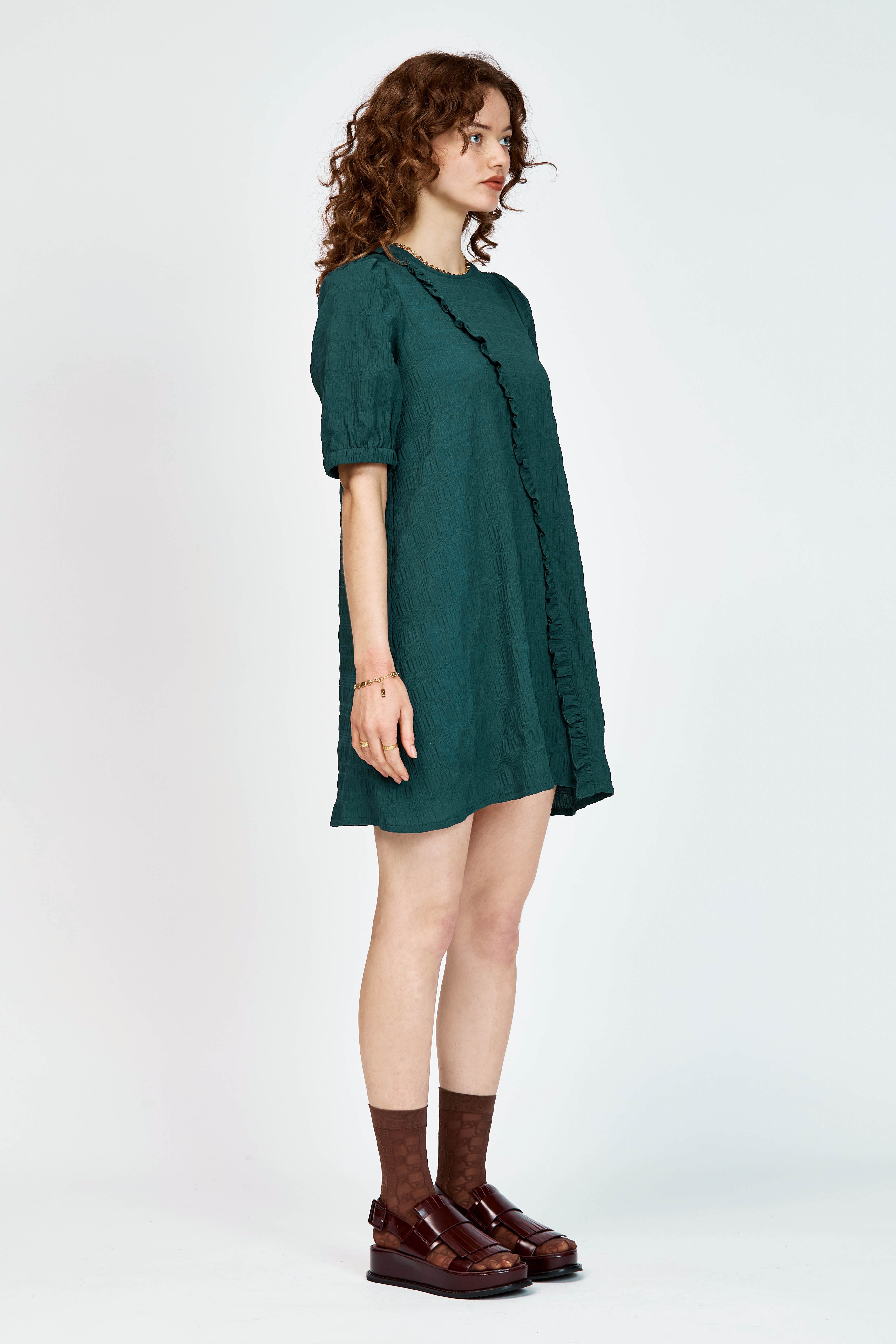 Model wearing a green mini dress with ruffle detailing