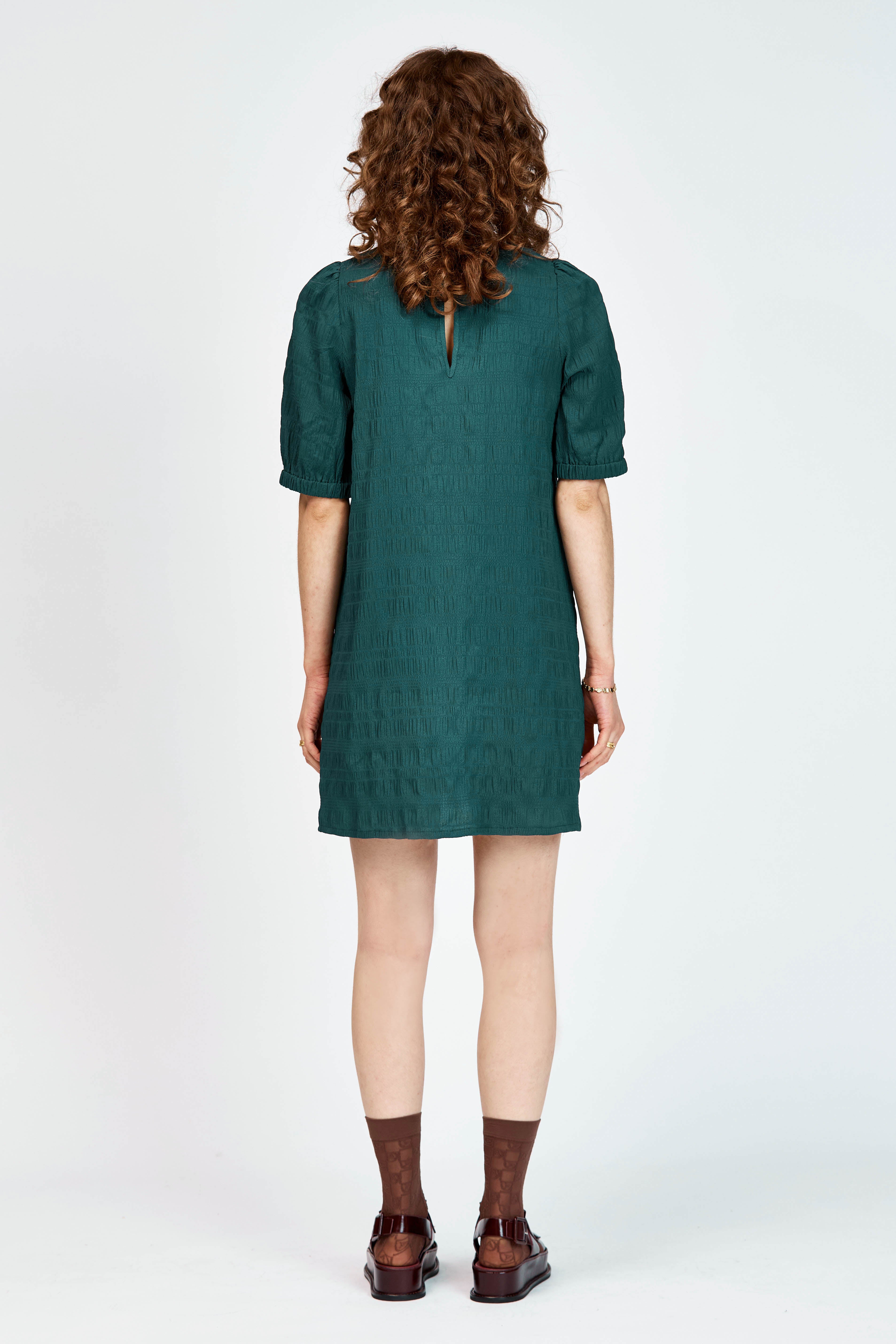 Model wearing a green mini dress with ruffle detailing