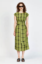 Model wearing an olive and black check midi length dress with a tie waist detail