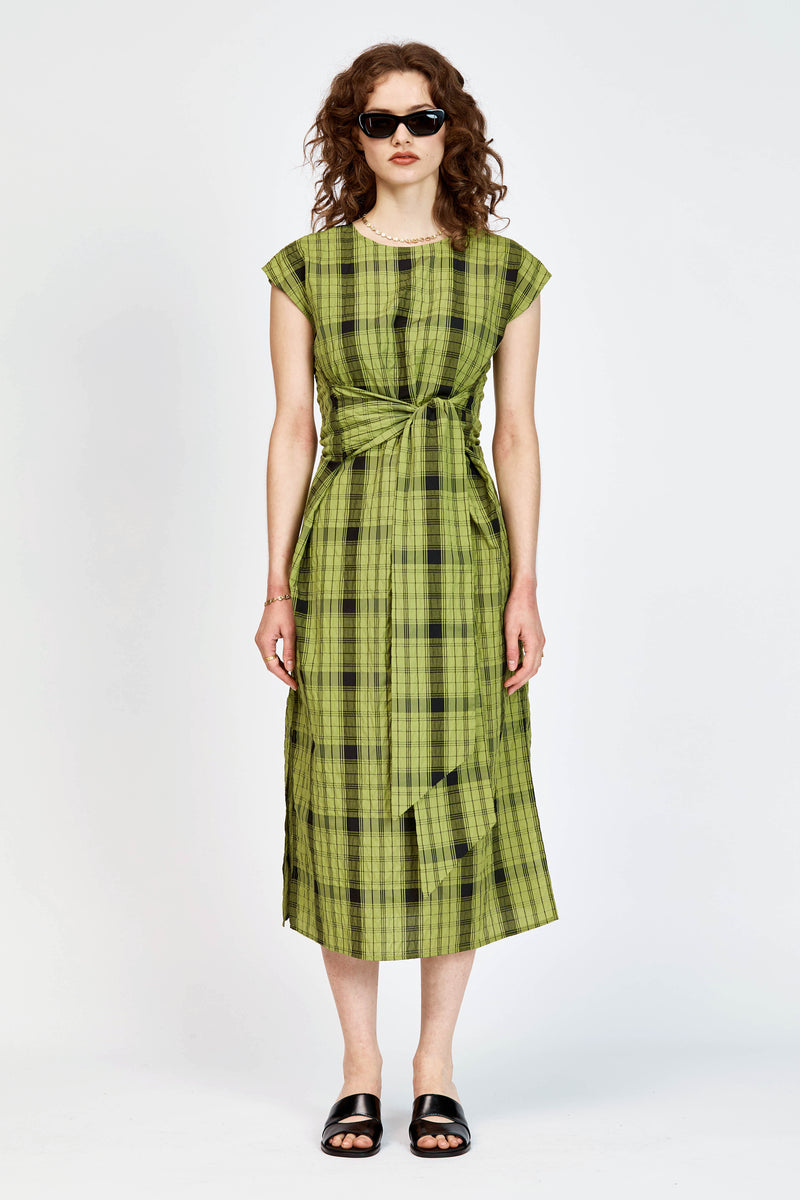 Model wearing an olive and black check midi length dress with a tie waist detail