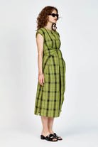Model wearing an olive and black check midi length dress with a tie waist detail