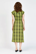 Model wearing an olive andblack check midi length dress with a tie waist detail