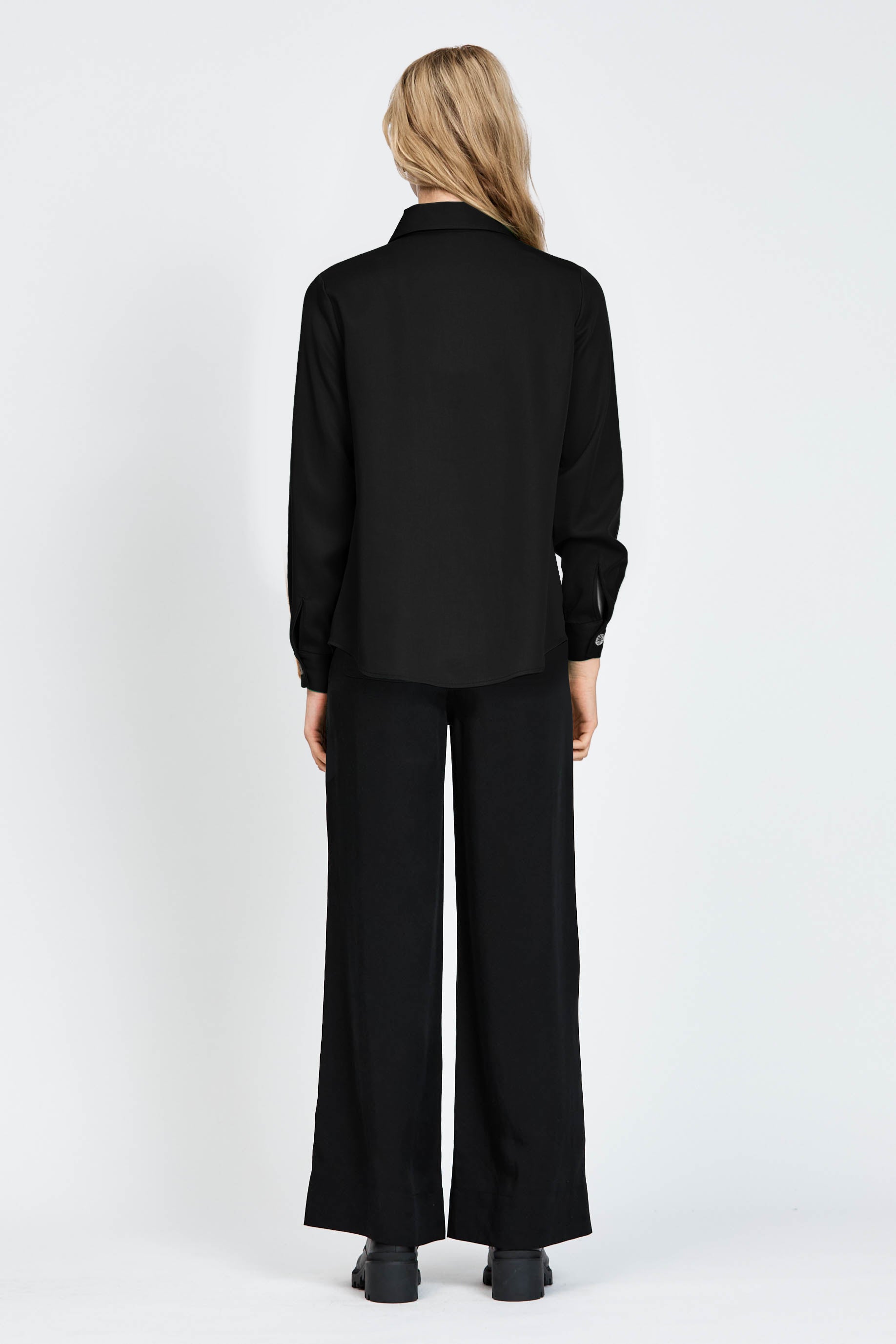Woman wearing a long sleeve black shirt with white buttons