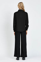 Woman wearing a long sleeve black shirt with white buttons